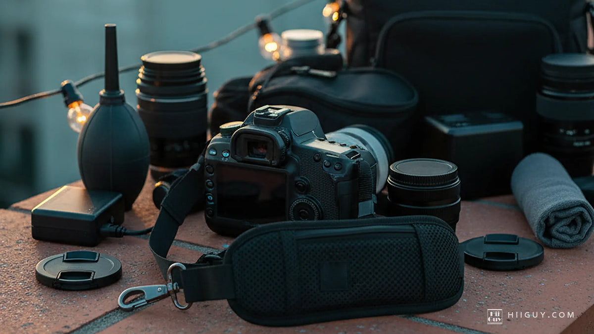 A beginner's camera kit on a warm terracotta rooftop ledge at dusk: a camera from behind, a padded strap, a blower, lenses and caps under lit bulbs.
