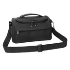 Black camera shoulder bag open to an orange padded interior, a small lens inside and a hand lowering a zoom lens in