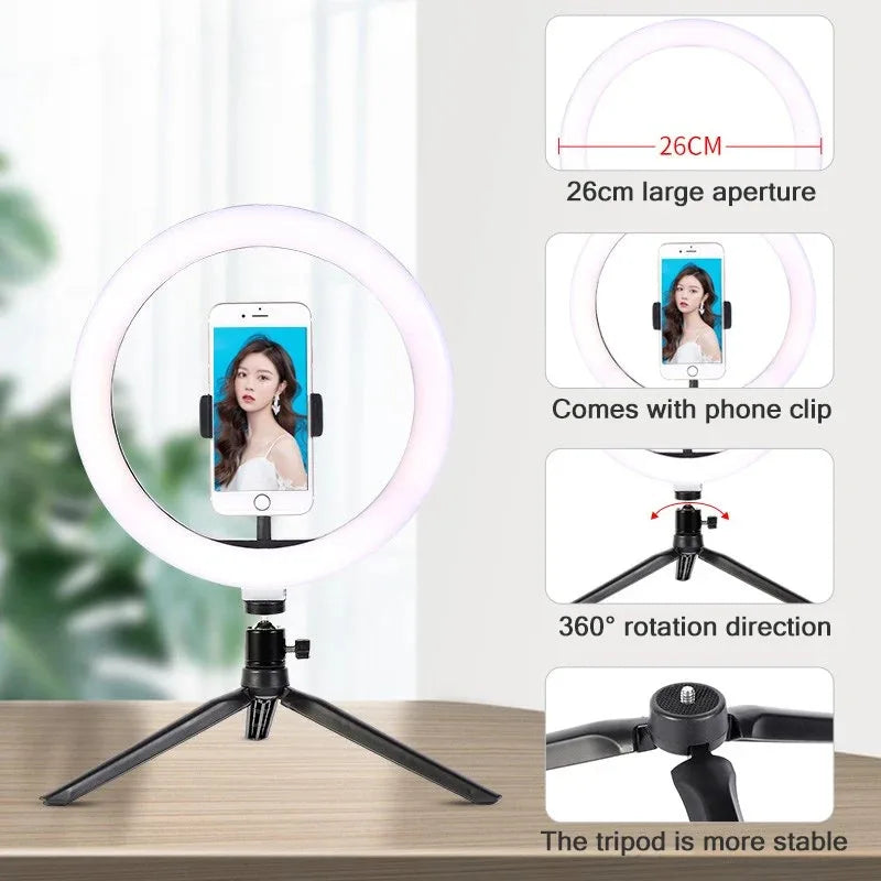 LED ring light on a small black tripod holding a phone on a makeup table, with a woman applying blusher behind it