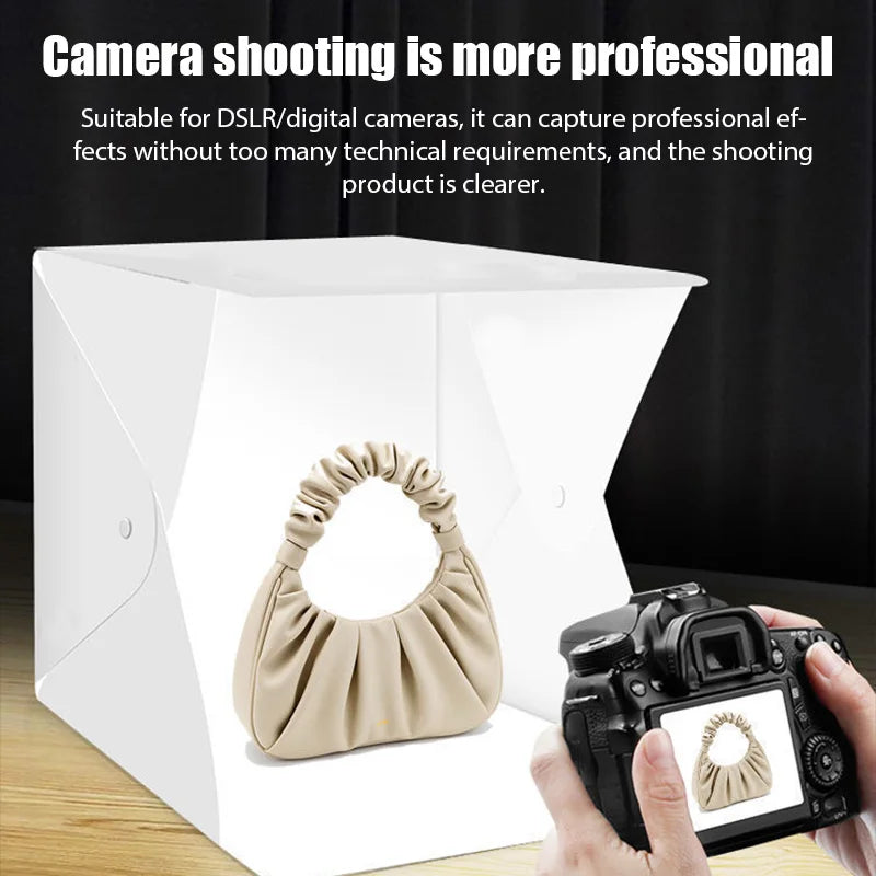 Small white folding light box with a strip of LEDs along the top edge, a cable and a power adapter, on a black background