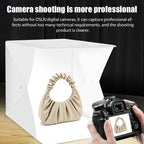 Small white folding light box with a strip of LEDs along the top edge, a cable and a power adapter, on a black background