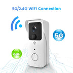 White video doorbell with a camera and a ring button, shown with a white plug-in chime and two blue batteries