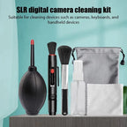 Camera cleaning kit on a shelf: black air blower, lens pen, soft brush, empty spray bottle, cloth and gray drawstring pouch