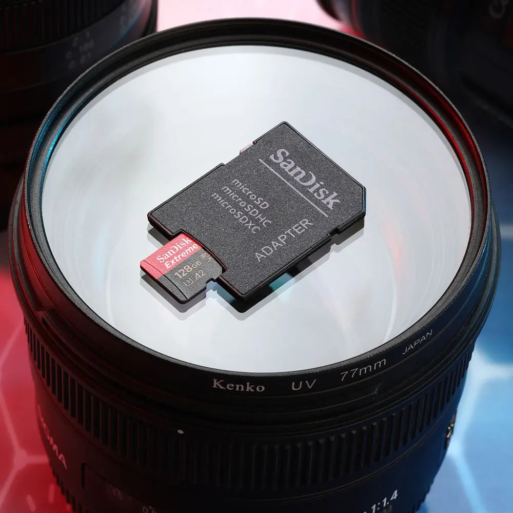 A SanDisk Extreme Pro 128GB microSD card and a SanDisk Extreme card in a black SD adapter on a pink background