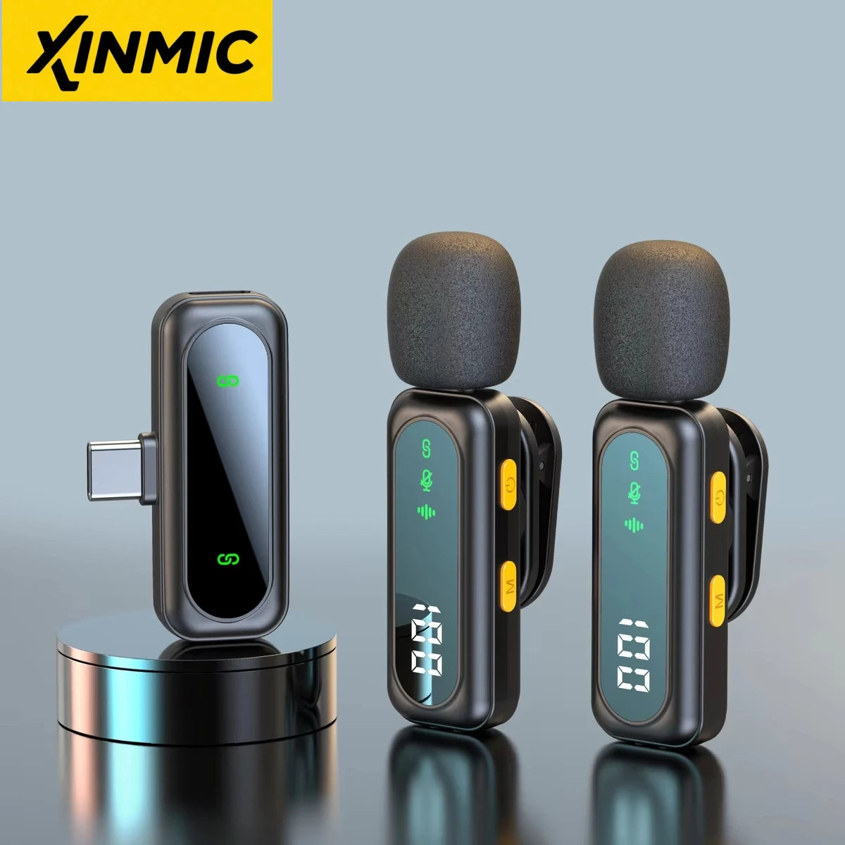 Black USB-C wireless receiver beside two clip-on transmitters with foam windscreens, digital displays and yellow buttons