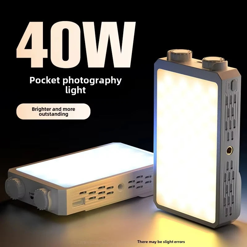 Two pocket-sized LED panel lights with control dials, one champagne and one grey, glowing warm white on a dark surface