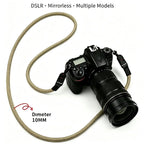 Black braided rope camera strap coiled on a dark surface, with a quick release clip and a cord loop at each end