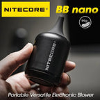 Hand holding a small black Nitecore BB Nano electric blower with a tapered rubber nozzle