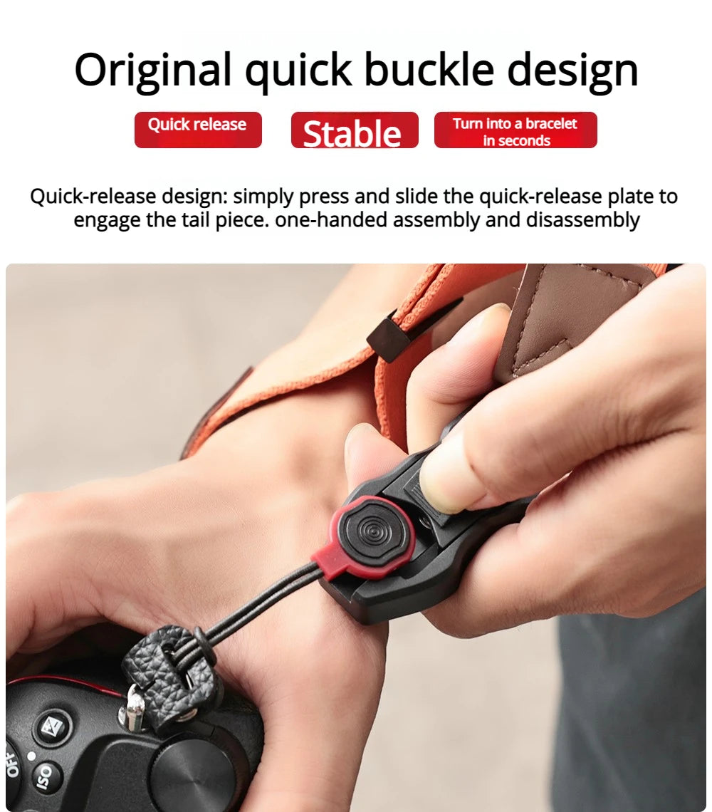 Orange camera wrist strap with a black clip worn on a wrist, the hand holding a black mirrorless camera