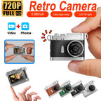 Tiny silver and black retro-style camera held between two fingers, its lens dial printed 1280x720P