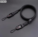 Black braided rope camera strap coiled on a dark surface, with a quick release clip and a cord loop at each end