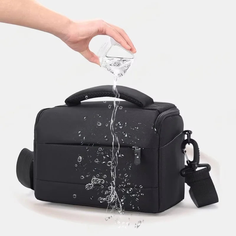 Black camera shoulder bag with a padded top handle, a zip front pocket and a clip-on shoulder strap