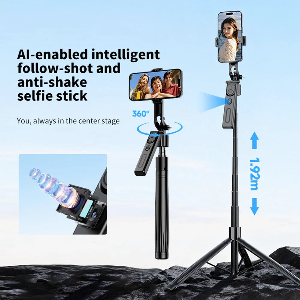 Black selfie stick tripod with a rotating phone mount and a detachable remote, extended tall on rocks with a phone on top