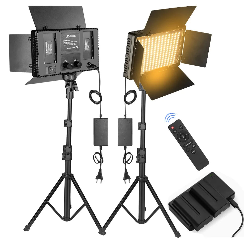 Two LED panel lights with barn doors on tall tripod stands, one lit warm, with power adapters, a remote and a battery
