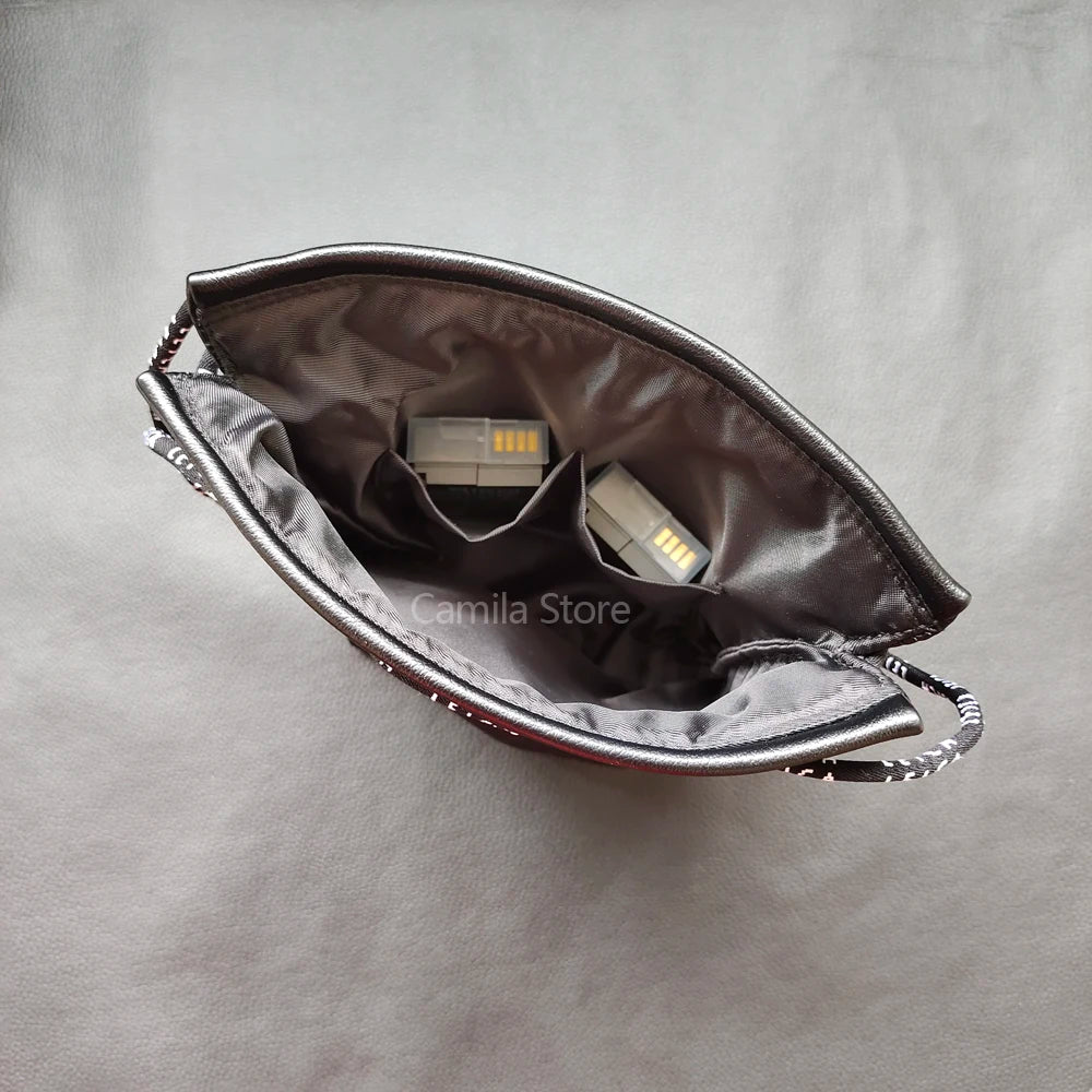 Black leather drawstring pouch opened around a compact camera with a round lens cap, on a store counter