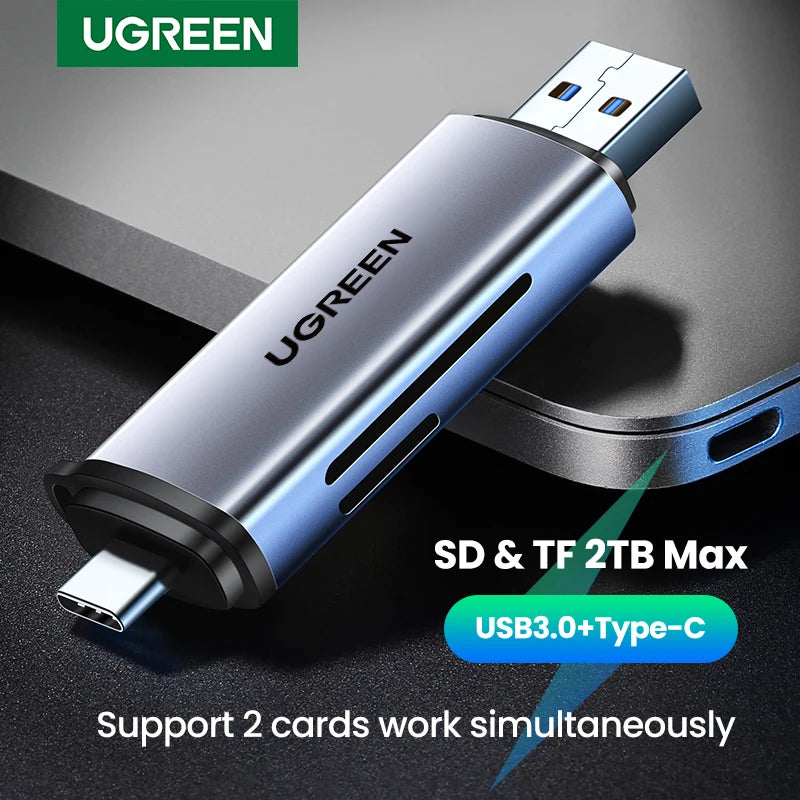 Grey metal card reader with a USB-A plug at one end and a USB-C plug at the other, resting on a dark laptop lid