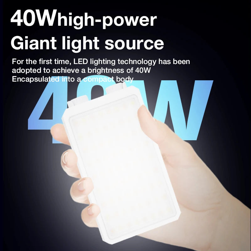 A white pocket-sized LED panel light glowing warm white, held in one hand against a dark background