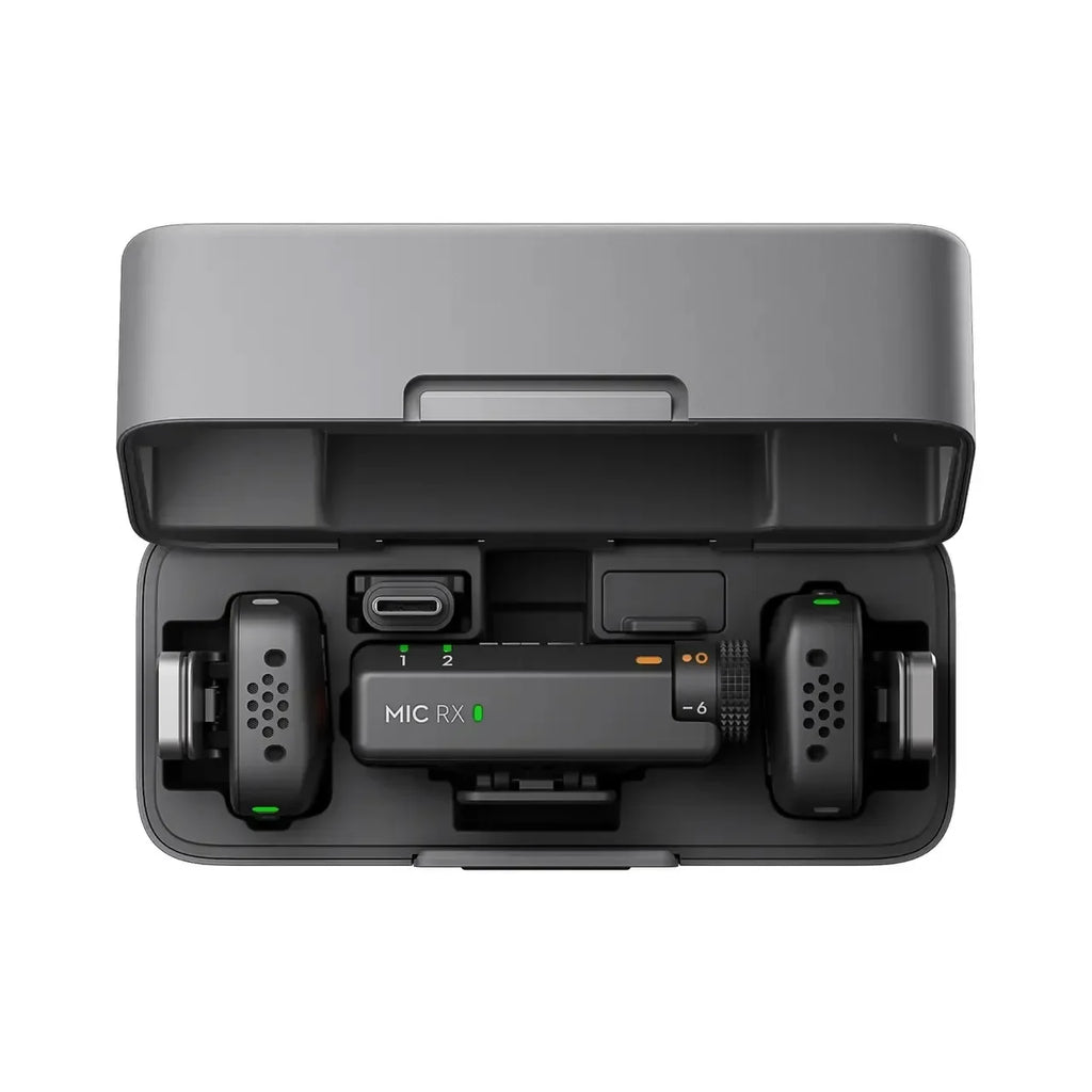 Black DJI Mic Mini charging case open, holding two small transmitters with gray furry windscreens