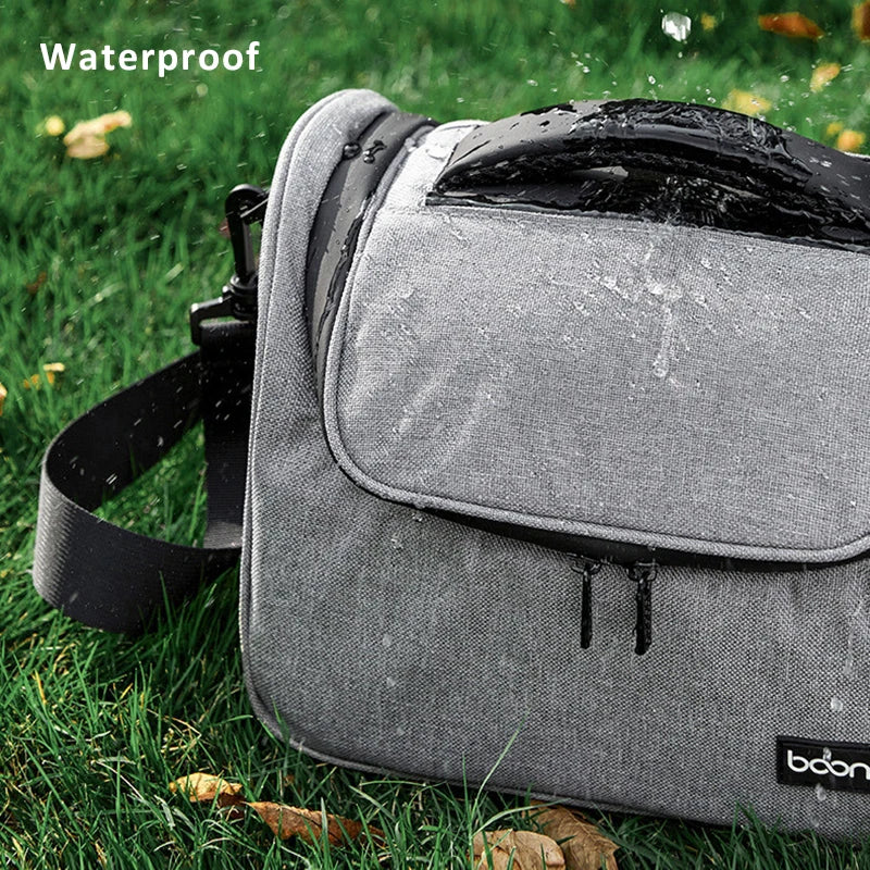 Grey camera shoulder bag with a black top handle and strap, beside an open one holding a DSLR and a lens