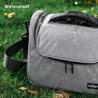 Grey camera shoulder bag with a black top handle and strap, beside an open one holding a DSLR and a lens