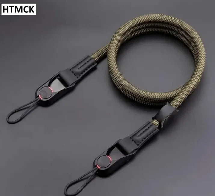 Black braided rope camera strap coiled on a dark surface, with a quick release clip and a cord loop at each end