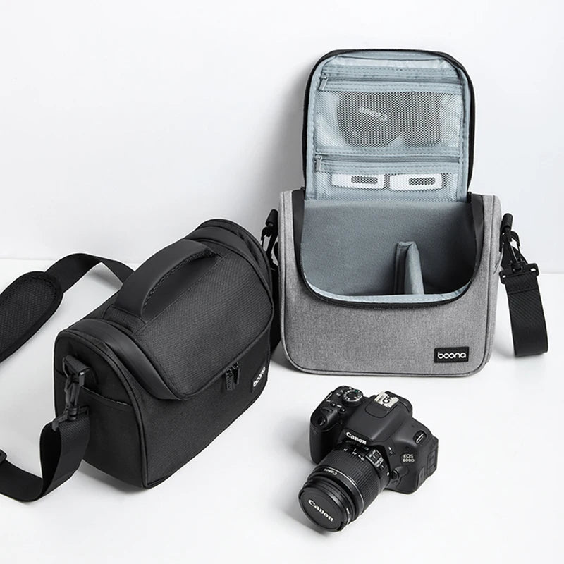 Grey camera shoulder bag with a black top handle and strap, beside an open one holding a DSLR and a lens