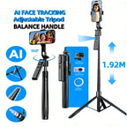 Black selfie stick tripod with a rotating phone mount and a detachable remote, extended tall on rocks with a phone on top
