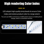 Small white folding light box with a strip of LEDs along the top edge, a cable and a power adapter, on a black background