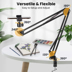 Black spring-loaded desk arm clamped to a table holding a phone, with a remote, ball head, phone clip and clamp laid out