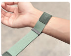 Orange camera wrist strap with a black clip worn on a wrist, the hand holding a black mirrorless camera