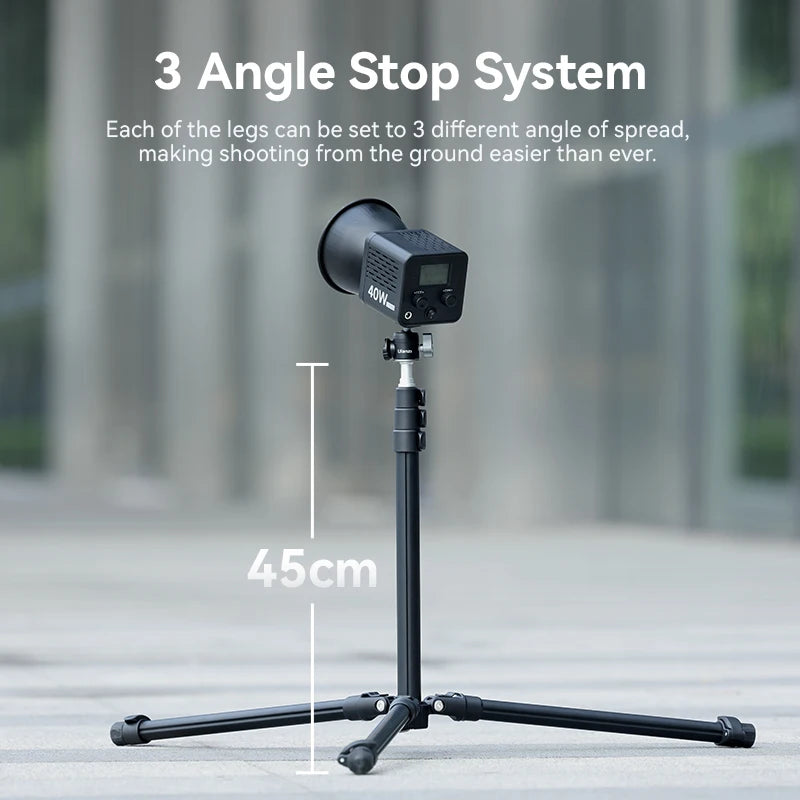 Black Ulanzi light stand with three legs and a stud on top, shown folded compact and being packed into a travel bag