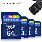 Four blue Microdrive Class 10 SD cards stepped in a row, with a Canon DSLR lens in the top corner