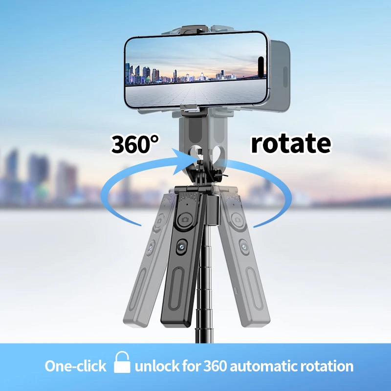 Black selfie stick tripod with a rotating phone mount and a detachable remote, extended tall on rocks with a phone on top